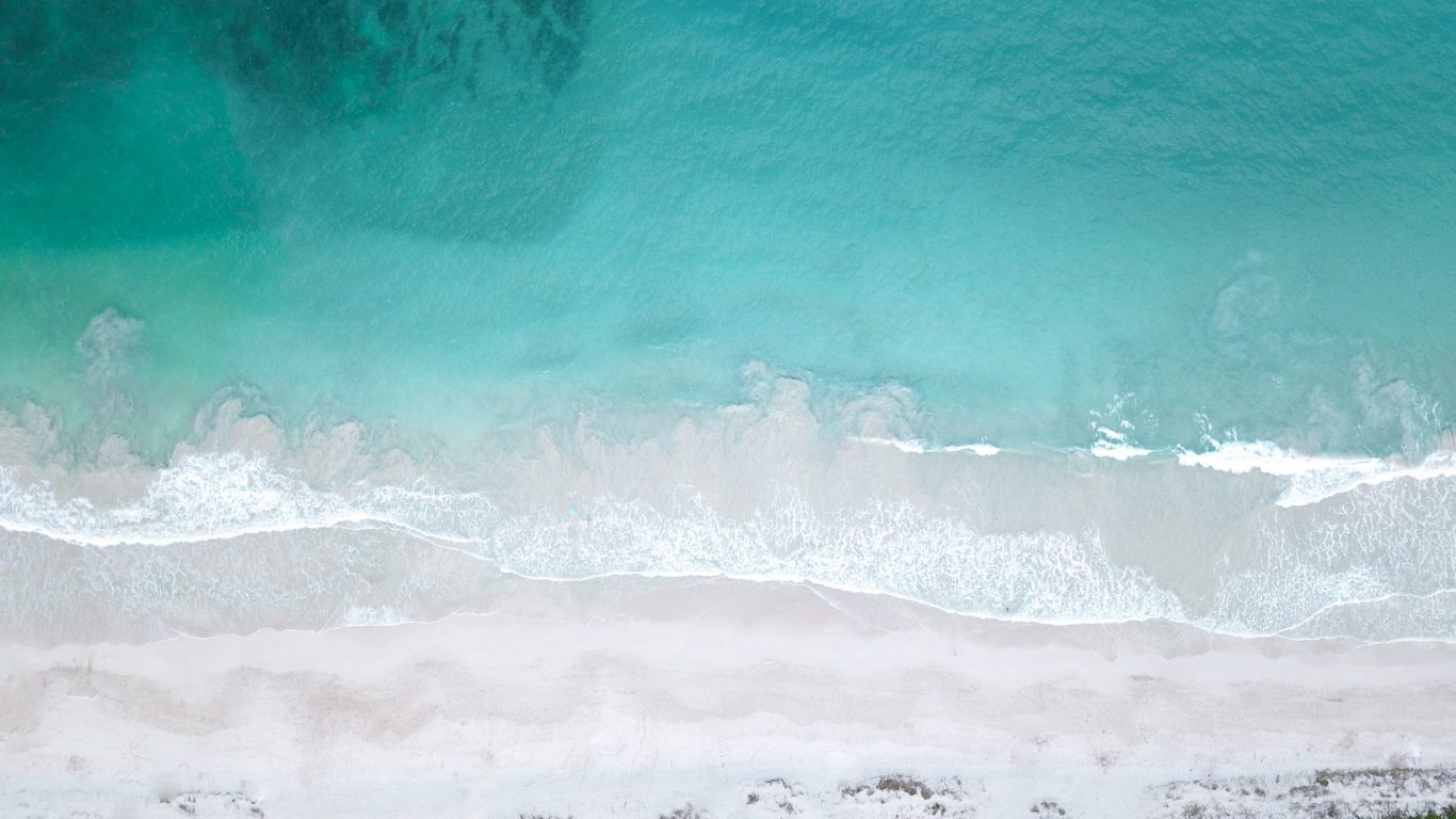 Foto van een helderblauwe zee met branding op slowcialmedia waarbij je gefocust kunt werken